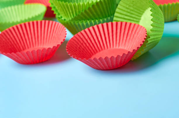 istock Red and green paper molds for baking muffins scattered on blue desk on kitchen. Space for text 1277958225