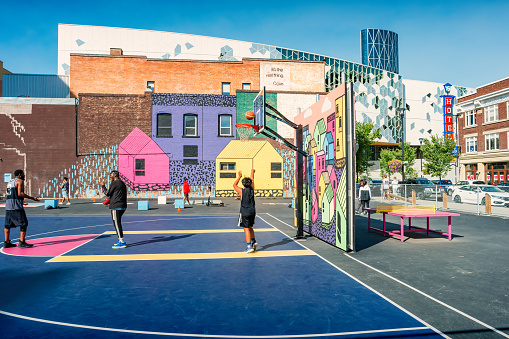 People play on a community basketball court in downtown Calgary, Alberta, Canada on a sunny day