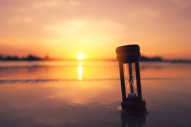 istock Hourglass on sand beach with sunset sky background. Vintage tone filter effect color style. 1277959933
