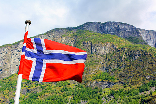 The national flag of Norway in the rough wind and blue sky with clouds.
