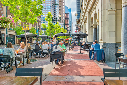 People dine on the patio of a restaurant on Stephen Avenue Walk in downtown Calgary Alberta Canada on a sunny day.