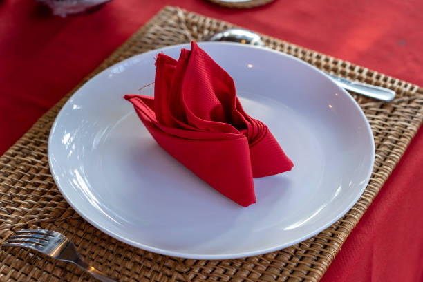 istock Elegant table setting with fork, spoon, white plate and red napkin in restaurant . Nice dining table set with arranged silverware and napkins 1277962493