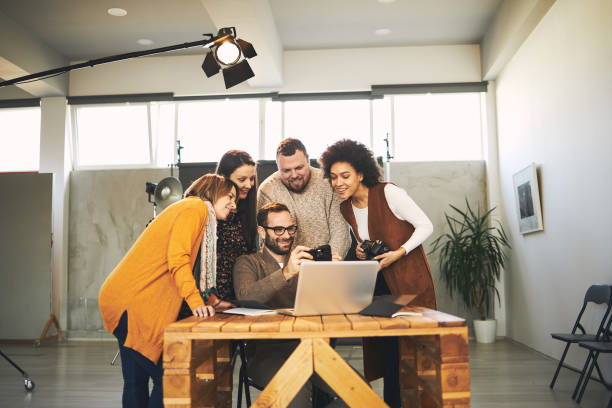 istock Small group of cheerful attendees standing in studio smiling and listening to their tutor talking about photography. 1277965543