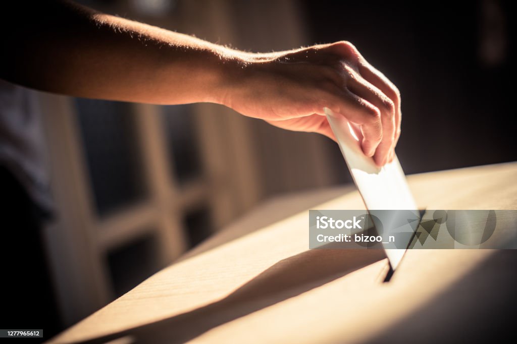 Conceptual image of a person voting during elections Conceptual image of a person voting, casting a ballot at a polling station, during elections. Voting Stock Photo