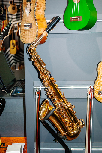 Brass saxophone woodwind instrument and wooden guitars selling in music store