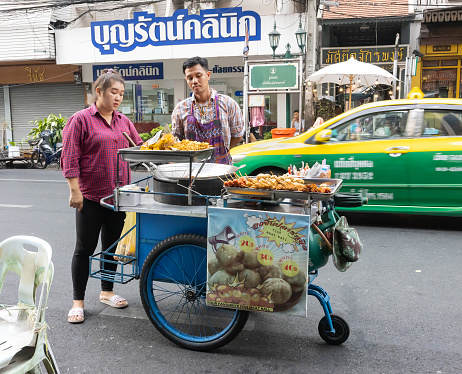 Bangkok, Thailand - February 27th, 2020: A traditional food vendor and a client, on a Bangkok street.