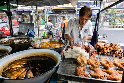 Bangkok, Thailand - February 27th, 2020: A traditional street food vendor, selling fish and chicken on a Bangkok street.