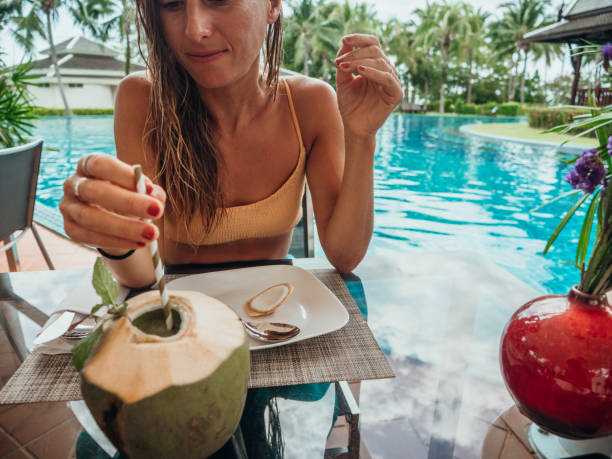 istock Woman drinking from coconut by the poolside 1277975454