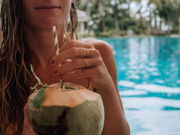 istock Woman drinking from coconut by the poolside 1277975515