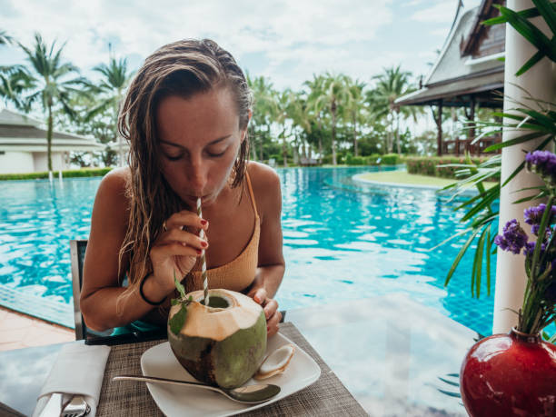 Woman drinking from coconut by the poolside
