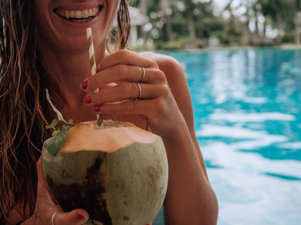 istock Woman drinking from coconut by the poolside 1277975587