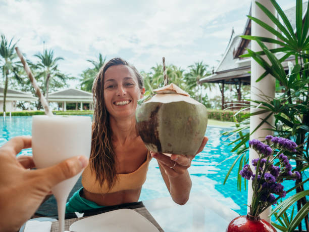 istock Couple cheering with fresh drinks by the poolside 1277975603