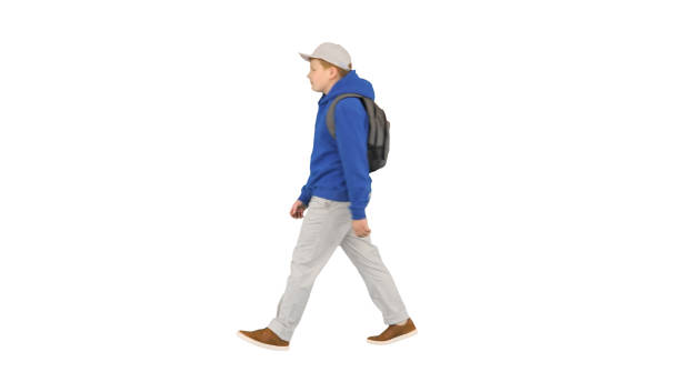 istock Young boy wearing a backpack walking to school on white backgrou 1277979228
