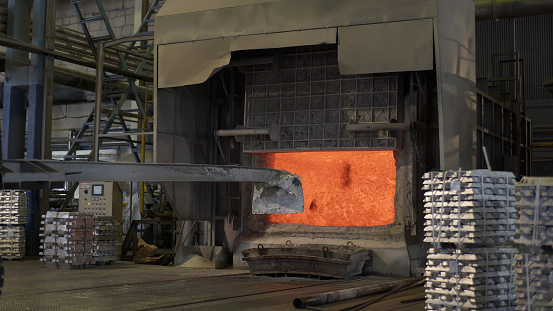 Aluminium foundry furnace loaded with metal. red hot flames glowing and liquid melting