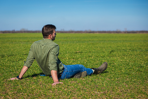 Young farmer sitting in wheat field.