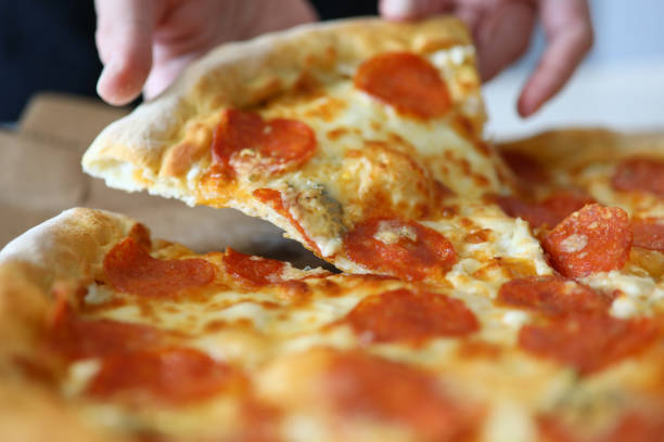 istock Close-up hands take slice pizza with sausages 1277984250