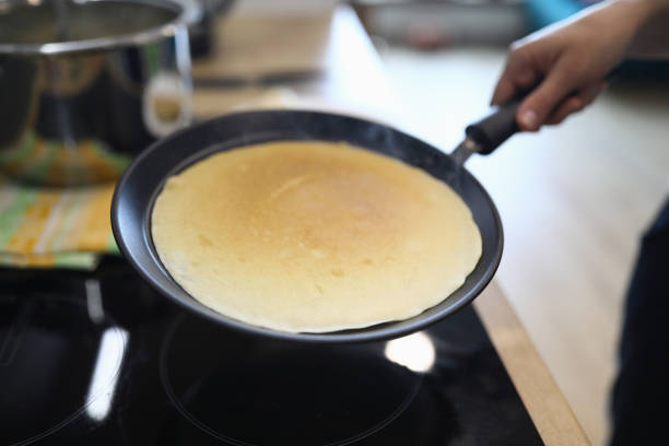 Hand holds pan with pancake, cooking at home. Available products, home recipes. Main types breakfast. Rules for working with toppings and assembly popular pies. Gluten free dough
