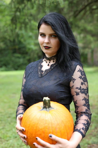 Smiling woman dressed in black holding a pumpkin