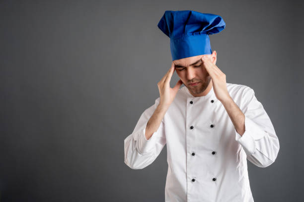 istock Young male dressed in a white chef suit has headache 1277987875