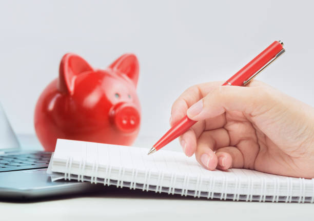 istock Hand writing and red piggy coins bank 1277988166