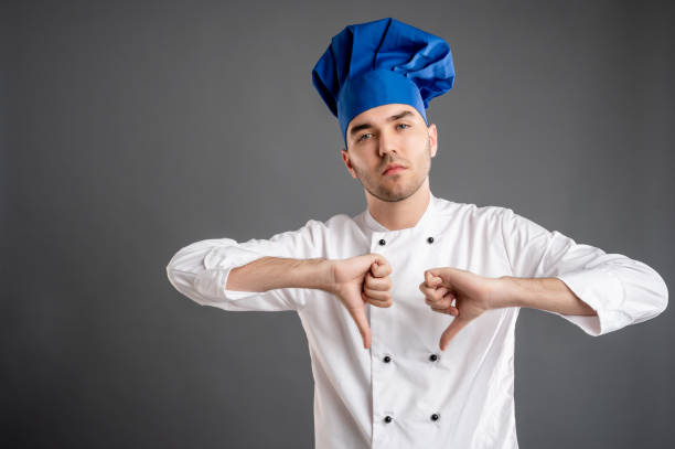 istock Young male dressed in a white chef suit showing double dislike 1277988237