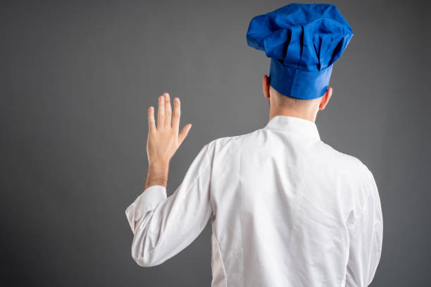 istock Young male dressed in a white chef suit showing oath from behind 1277988446