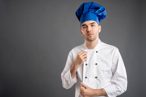 istock Young male dressed in a white chef suit arranges his uniform 1277989978