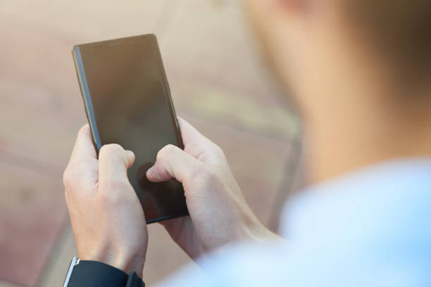 istock Rear view of a man using smartphone while spending time outdoors, focus on mobile phone 1277990572