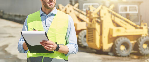 istock Young civil engineer wearing helmet writing report while standing at construction site 1277990709