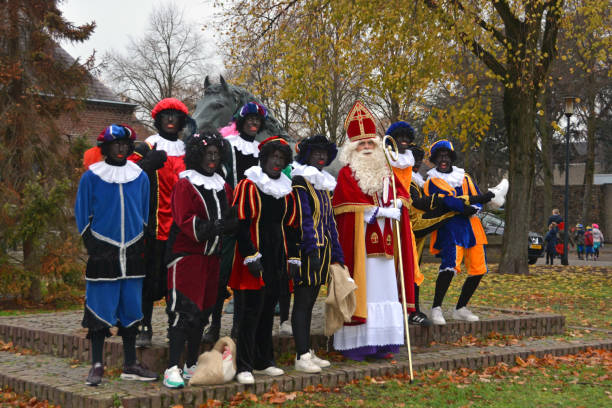 Santa Claus festival. Nuenen-Netherlands;  25 november 2018. Sinterklaas / Sint-Nicolaas arrived in small town Nuenen . Sinterklaas and Zwarte Pieten standing together in the city centre. Sinterklaas is an icon and a folklore and  from centuries an old tradition. Feast with gifts for the children on December 5th. Local residents in a temporary role position. zwarte piet stock pictures, royalty-free photos & images