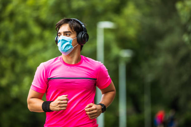 istock Young man in face mask jogging in park during quarantine. Copy space 1278003925