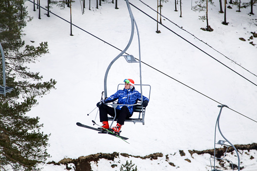 Young male skier on a ski resort, riding on a ski lift. About 20 years old, Caucasian male.