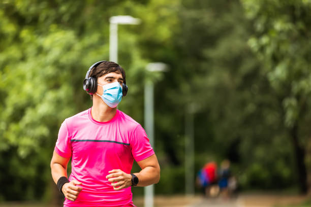 istock Young man in face mask jogging in park during quarantine. Copy space 1278004406