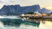 Norway, Lofotens, Sakrisoy village. Classic view of Lofoten Islands architecture - traditional wooden fishing houses rorbu at picturesque mountain peaks background during sunrise.