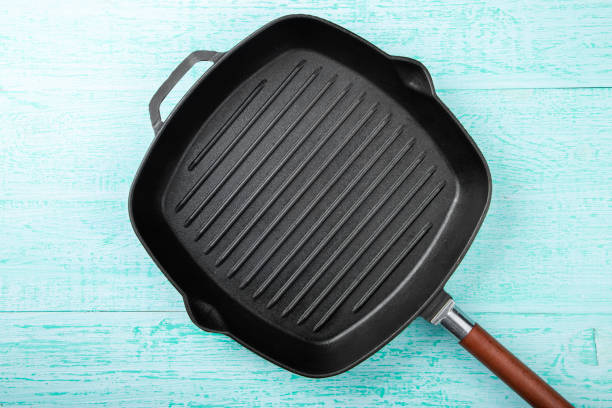 istock Black frying pan grill on a turquoise wooden background. Space for text. 1278008105