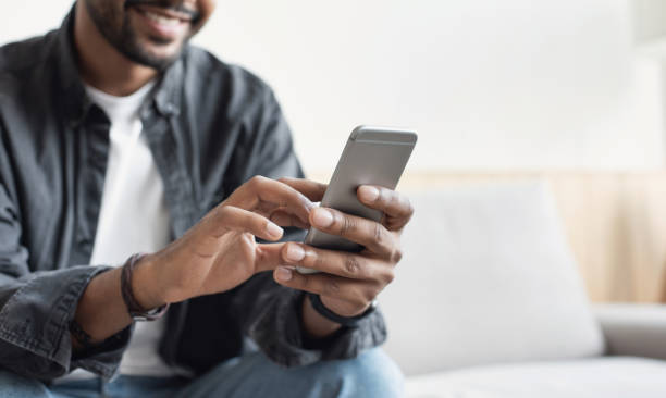 Young man using smart phone at home Young men using mobile phone. Business, communication, technology concept guy looking at cell phone stock pictures, royalty-free photos & images