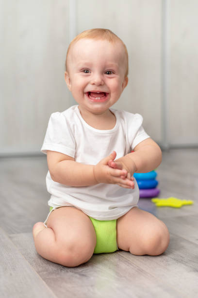 istock Cute baby laughing while sitting on the floor 1278010379