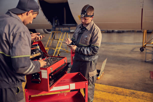 istock Two handsome seriously men in uniform using aviation equipments in the aviation hangar 1278011273