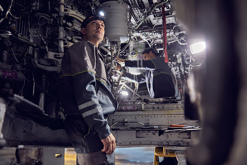 Close up portrait of confident man in uniform working inside of transport aircraft renewal technology with the modernization programe