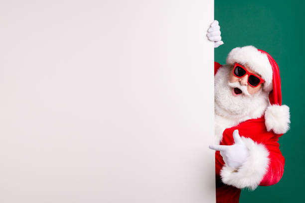 照片退休時尚祖父白髮鬍子直接手指白色空板提供最佳選擇穿紅色 santa x-mas 服裝外套手套太陽鏡帽隔離綠色背景。 - santa claus 個照片及圖片檔