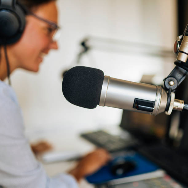 istock Microphone in a podcasting studio, host and the broadcasting equipment in the background 1278014671