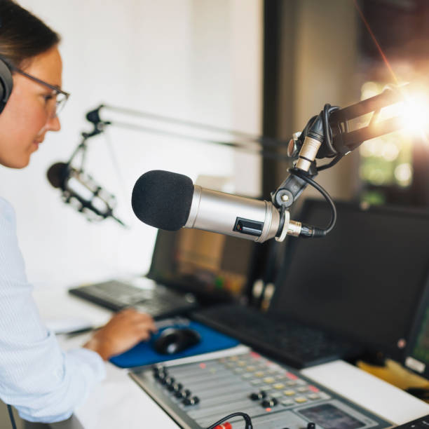 istock Microphone in a podcasting studio, host and the broadcasting equipment in the background 1278014700