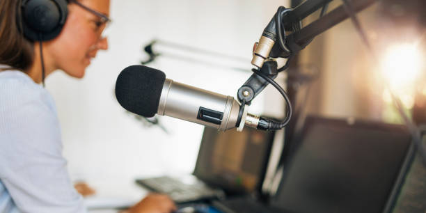 istock Microphone in a podcasting studio, host and the broadcasting equipment in the background 1278019451