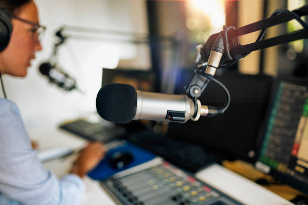 istock Microphone in a podcasting studio, host and the broadcasting equipment in the background 1278019559