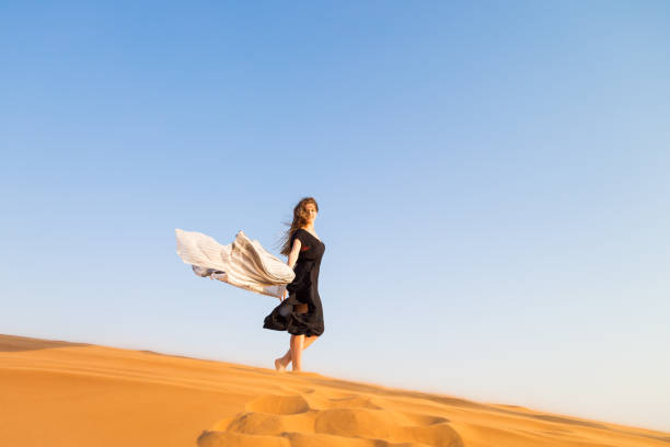 The girl closed her eyes from the wind and sand in the desert against the sky