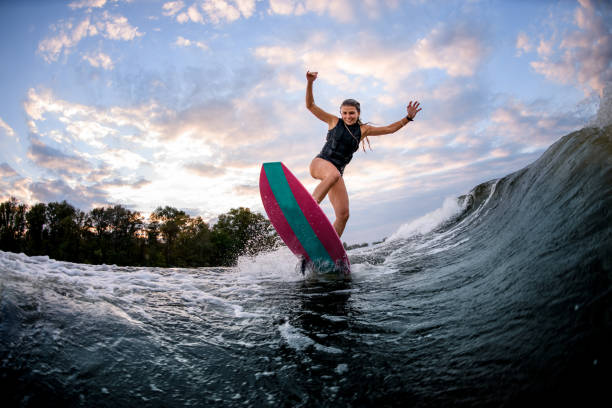 istock energetic young woman stands on surf style wakeboard and ride down on wave 1278023135