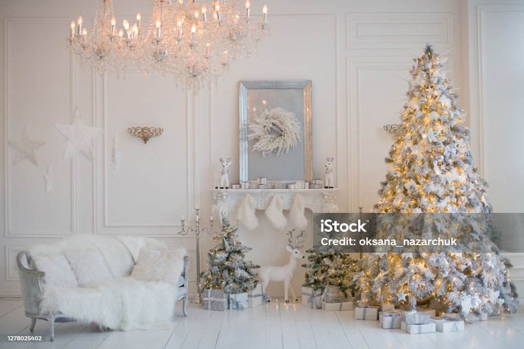 Cozy white Christmas interior room Cozy white Christmas interior room. Living room with Christmas tree, white sofa, crystal chandelier, fireplace and white and silver decorations Christmas Tree Stock Photo