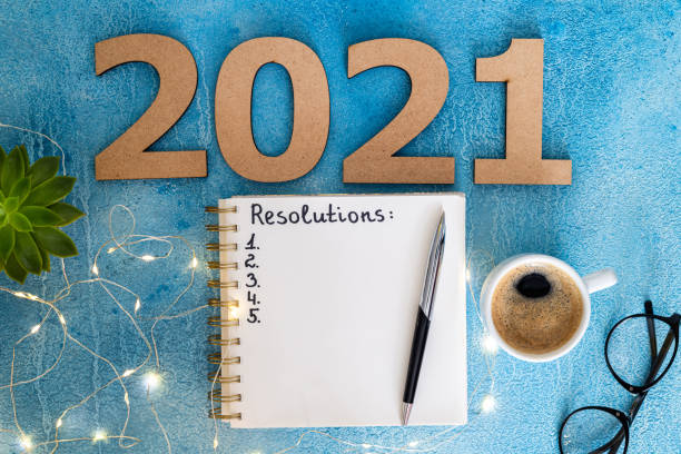 istock New year resolutions 2021 on desk. 2021 goals with notebook, coffee cup and eyeglasses on blue background. Goal, plan, strategy, action, idea concept 1278026414