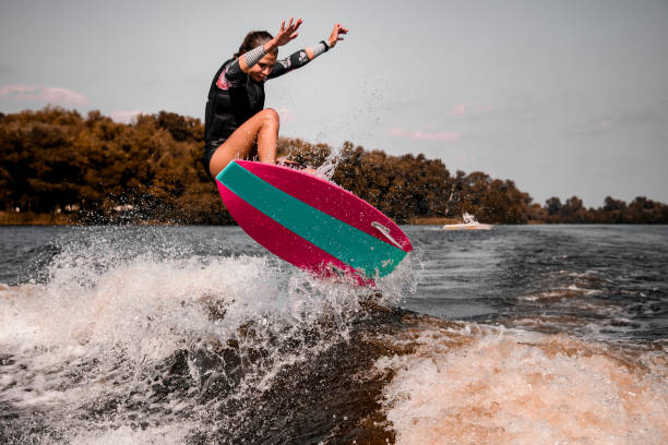 istock energetic young woman skillfully jumping over splashing river wave on surf style wakeboard. 1278027591