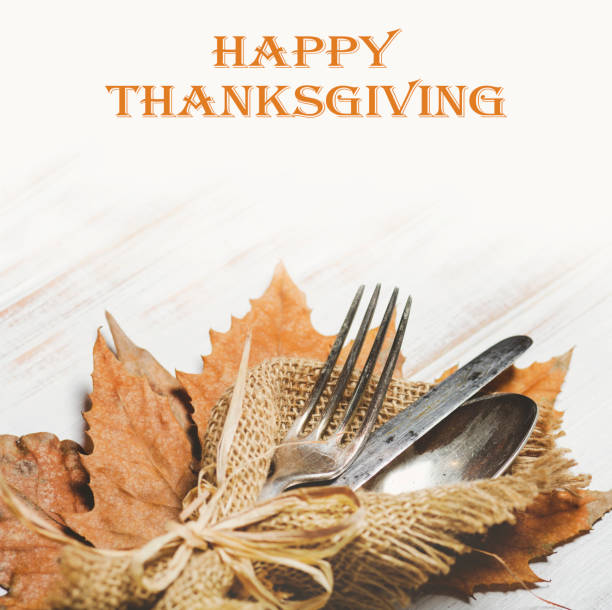 Thanksgiving dinner table setting with autumn leaves and vintage silverware.